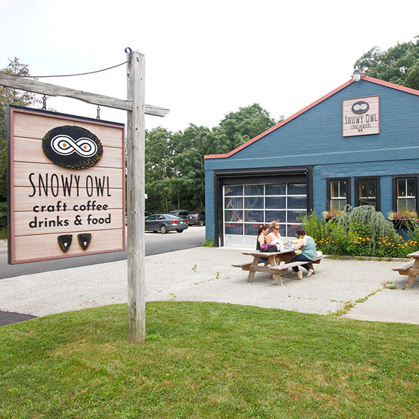 Welcoming exterior of Snowy Owl's Sandwich roastery and cafe features outdoor seating where guests can enjoy specialty coffee drinks, fresh pastries, and house-made empanadas.