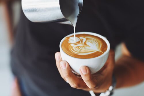 A barista pours milk into beautiful latte art at one of three Snowy Owl Coffee Roaster locations